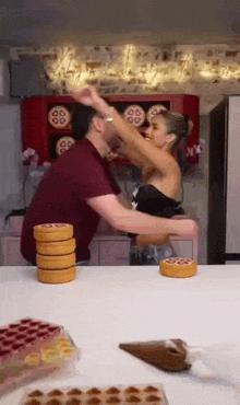 a man and a woman are playing a game of stacking cookies on a table .