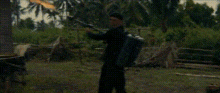 a man is holding a gun with a flame coming out of it in a field .