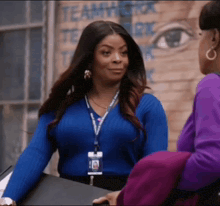 a woman wearing a blue sweater and a lanyard with a picture of a woman on it