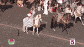 a group of people riding horses in a parade with a ktla 5 logo