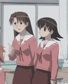 two anime girls are standing next to each other in a classroom . one of the girls is wearing glasses .