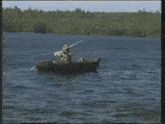 a man is rowing a boat in a lake with trees in the background
