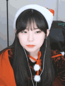a girl wearing a santa hat and ear buds