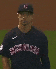 a baseball player wearing a cleveland jersey stands on a field