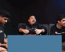 a man wearing a black champion sweatshirt sits next to another man