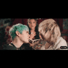 a man with green hair is standing next to another man with blonde hair .