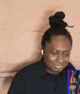 a man with dreadlocks in a bun is sitting in front of a screen with a picture of a woman on it .