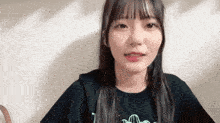 a young girl wearing a black shirt with the letter t on it is smiling