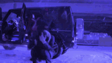 a group of people are standing in front of a black van in the snow