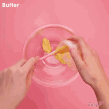 a glass bowl filled with dark liquid on a pink background .