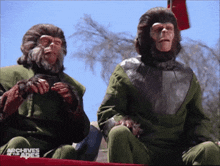 two monkeys are sitting on a red table with the words archives of the apes on the bottom right