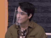 a man wearing a face shield and glasses is sitting in a chair .