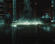 a man in a blue suit is standing in a dark room with a lot of water