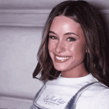 a woman wearing overalls and a white shirt that says dolce & gabbana