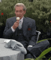 a man in a suit is sitting at a table eating ice cream