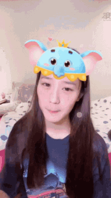 a girl wearing a blue elephant headband with a crown on top