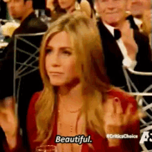 a woman sitting at a table with her hands in the air says beautiful