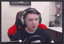 a young man wearing headphones and a microphone is sitting in a chair .
