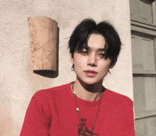 a young man wearing a red shirt is standing in front of a building