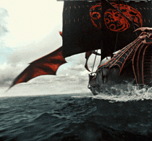 a ship with a dragon on the sails is floating in the ocean