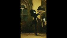 a woman in a black dress is dancing in a room with a table and chairs .
