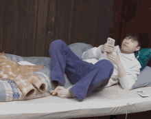 a man is laying on a bed looking at his cell phone