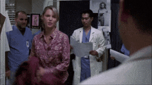 a woman in a pink shirt stands next to a man in a white coat with the letter l on it