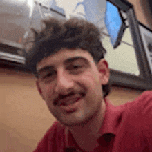 a man with a mustache is taking a selfie in a restaurant .