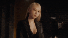 a woman with blonde hair is wearing a black jacket and black top