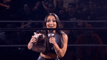 a woman in a wrestling ring holds a microphone that says wwe