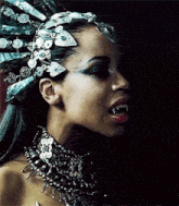 a woman with vampire teeth is wearing a crown and a necklace .
