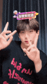 a man wearing a black shirt that says bloom on it is making a peace sign