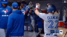 a blue jays player named clement high fives his teammates in the dugout