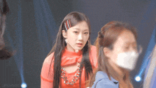 a woman wearing a face mask is standing next to another woman on a stage .