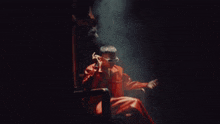 a man in a red suit and sunglasses is sitting in a chair