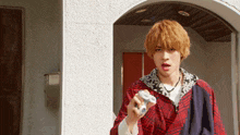 a young man in a plaid jacket is holding a remote control in his hand