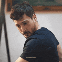 a man with a beard is wearing a black shirt and is looking over his shoulder .