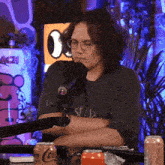 a man wearing glasses is sitting in front of a microphone with a can of coca cola in front of him