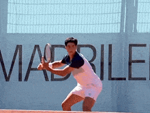 a man is playing tennis in front of a sign that says madrid