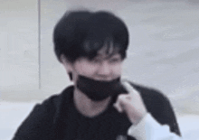 a young man wearing a black mask is looking at the camera .