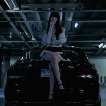 a woman sits on the back of a black car with a license plate number 505
