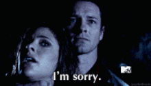 a man and a woman are standing next to each other and the woman is saying i 'm sorry