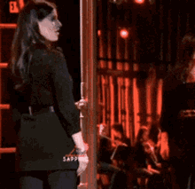 a woman in a black dress is standing in front of a sign that says saponic