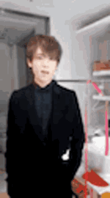 a man in a suit and tie is standing in a room with his hands in his pockets .