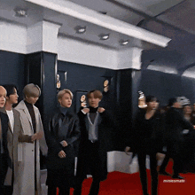 a group of people are standing on a red carpet with the name miniesmate on the bottom right