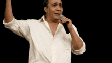 a man singing into a microphone with his hands in the air