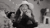 a little girl wearing a hat is sitting on a bed with stuffed animals .