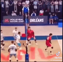 a group of volleyball players are playing volleyball on a court in front of a crowd .