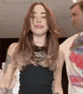 a woman in a black tank top is standing next to a man .