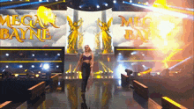 a woman is walking on a stage with megan bayne written on a large screen behind her